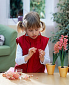 Girl threads hyacinth blossoms on a pearl string