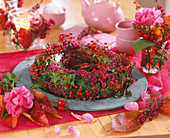 Wreath of pink (rose hips), Erica (potferica), Hedera (ivy) on a tin plate