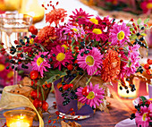 Chrysanthemum, Rosa / Hagebutten, Ligustrum / Ligusterbeeren in lila Glasbecher