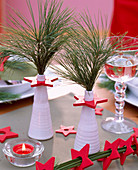 Pinus strobus / Seidenkiefer in weißen Vasen, rote Holzsterne, rotes Teelicht