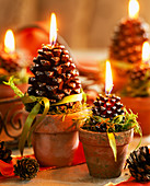 Pine cone candles in clay pots, moss