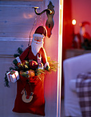 Father Christmas with a red felt bag hung on a door handle, Pinus (pine), Abies (fir)