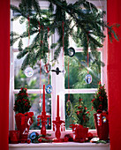 Picea (Zuckerhutfichten) in roten Töpfen und Zweig im Fenster mit Glasanhängern