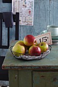 Apples arranged in a wire basket on a wooden cabinet