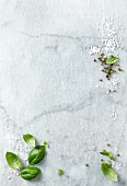 Basil leaves, sea salt and green peppercorns on a marble platter