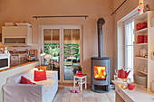 Lit fire in open-plan living room decorate in white and red