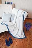 Blanket with blue crocheted trim on white armchair in rustic living room