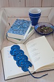 Blaues, gehäkeltes Lesezeichen im aufgeschlagenen Buch