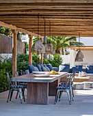 Dining table and lounge area under summery pergola