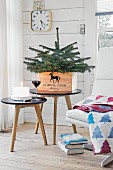 Kleiner Weihnachtsbaum in einer Holzkiste auf einem Beistelltisch