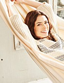 A brunette woman in a striped jumper lying in a hammock