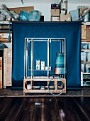 A machine in front of a blue background in the storeroom, designed by Katharina Mischer and Thomas Traxler