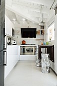weiße Einbauküche mit hellem Boden und Frühstückstisch