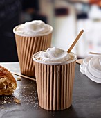 Cappuccino in zwei To-Go-Pappbechern mit Croissant