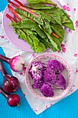 An arrangement of beetroot leaves, red onion and purple cauliflower
