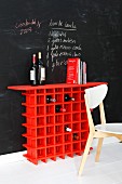 Rotes Weinregal vor einer Wand mit Tafelfarbe mit notiertem Rezept