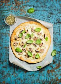 Homemade mushroom pizza with basil leaves and spices in glass on baking paper