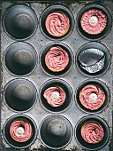 Pink iced cupcakes in a baking tray