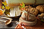 Herbstliches Buffet mit Kürbissen, Landbrot und Gläsern auf Tablett