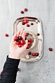 A child's hand holds cranberries above a silver tray