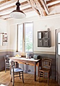 Rustic kitchen table, wooden chairs and vintage post boxes hung on wall