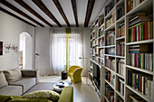Wohnzimmer mit großer Bücherwand und Balkendecke
