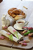 Rolled linen napkins tied with tulips petals and green lace ribbons on aster breakfast table
