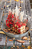 Tischgesteck aus Walnüssen, Schilf und roten Beeren