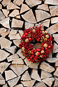 Wreath of red berries, walnuts and medlars on stacked firewood