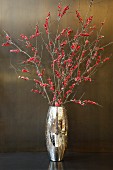 Branches of red berries in gold vase