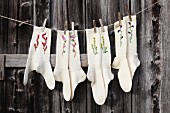 Hand-knitted woollen socks embroidered with flowers hung from washing line