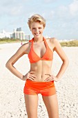 Blonde Frau in orangefarbenem Bikini am Strand