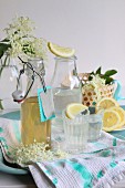 Holunderblütensirup in Bügelflasche und eingeschenkten Gläsern mit Zitronenscheiben
