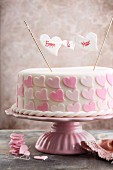 A romantic pink 'Will you...' cake with icing hearts
