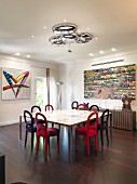 Velvet chairs around table in front of sideboard and modern artwork