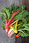 Various different coloured chard on a wooden surface