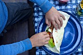 A child's hands rolling a filled burrito