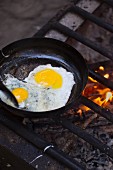 A fried egg in a pan on a fire grate (camping breakfast)