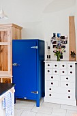 Blauer Kühlschrank neben weißem Schubladenschrank in Landhausküche