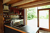 Wood-beamed ceiling in open-plan kitchen with view of garden
