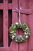 Romantic Easter wreath hung on claret-red garden gate