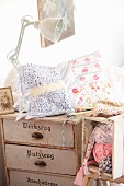 Patchwork cushion and knitting on top of old chest of drawers
