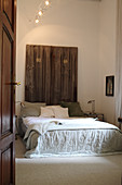 Disused wooden doors used as headboard of double bed in bedroom