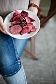 A woman holding a plate of beetroot chips