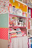 Fabric remnants, tubes of paint and screw-top jars on colourful shelves