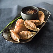 Potstickers (Asiatische gefüllte Teigtäschchen) mit Sauce auf Tablett