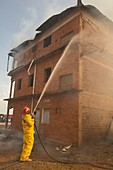 Firefighter using a hose on a burning building