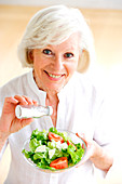 Woman adding salt on a salad