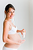 Pregnant woman applying cream