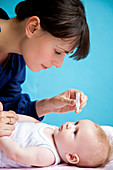 Mother putting eye-drops in baby's eyes